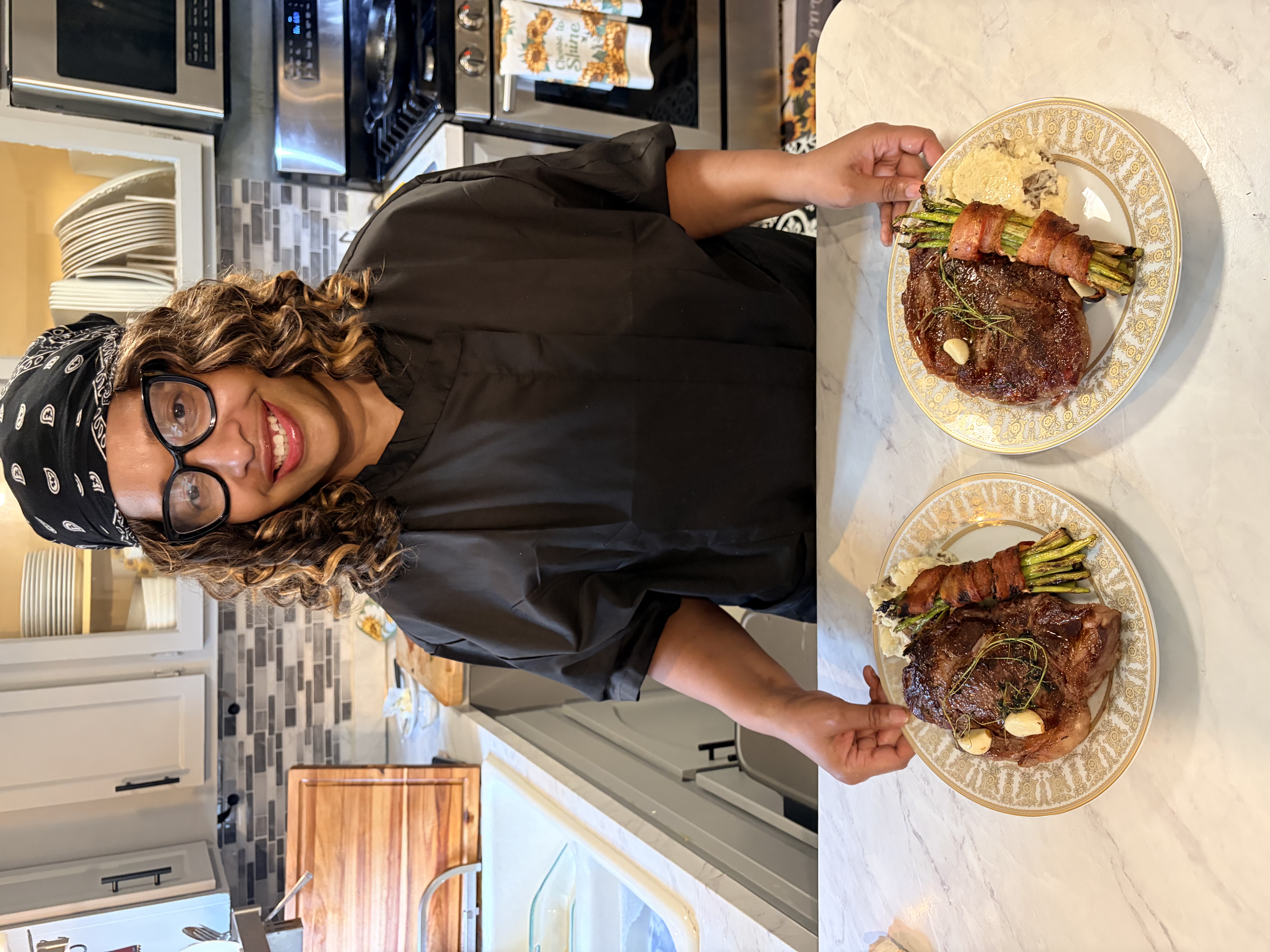 Chef Shorlanda presenting seared steak dinners with asparagus and mashed potatoes